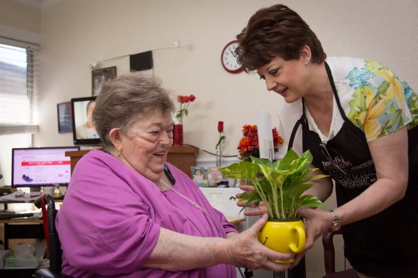 Florist, Mary Ann DeBerry, right, hands resident Dorothy Martin a flower arrangement at the...