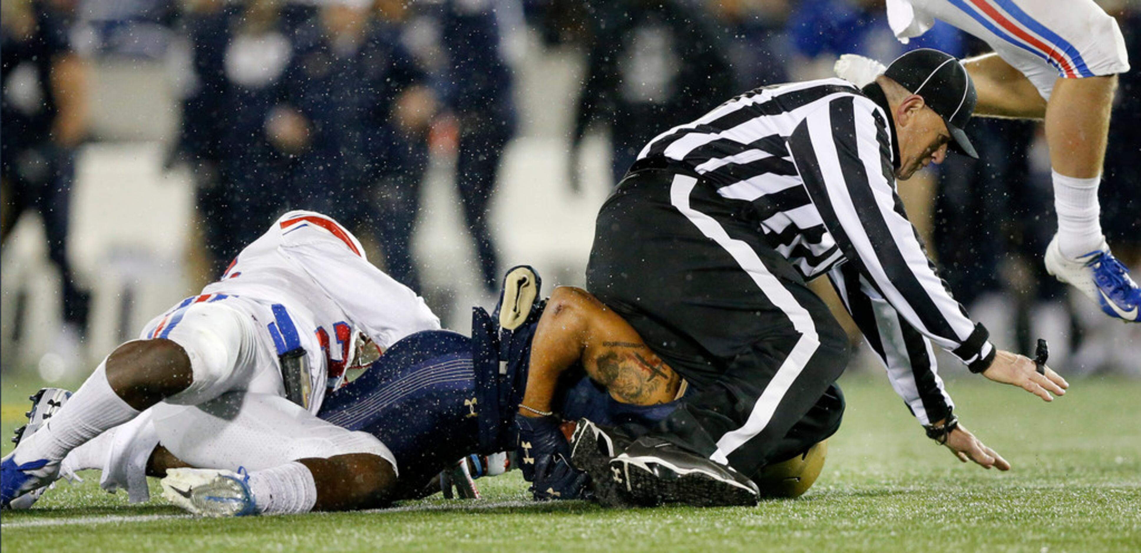 An official is taken down by Navy Midshipmen wide receiver Chance Warren (13) as he tried to...