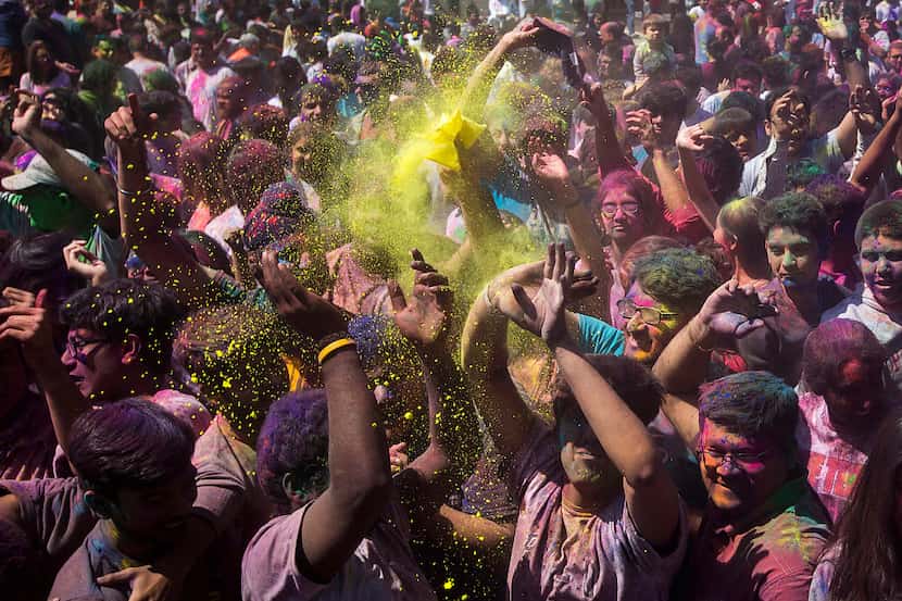 Celebrants dance as colored powder is thrown into the air during festivities celebrating the...