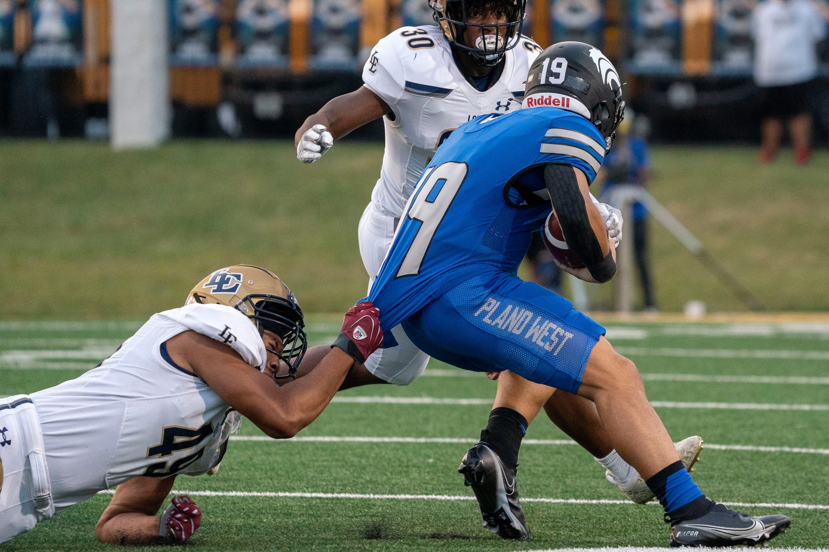 Little Elm senior defensive lineman Troy Walker (49) drags down Plano West junior running...