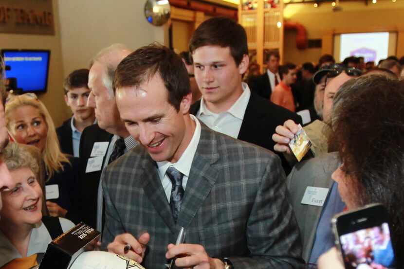 New Orleans Saints NFL football quarterback Drew Brees signs a football at a reception...