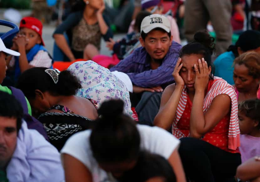 Exhausted migrants wait in lines to board a handful of buses provided to transport some of...