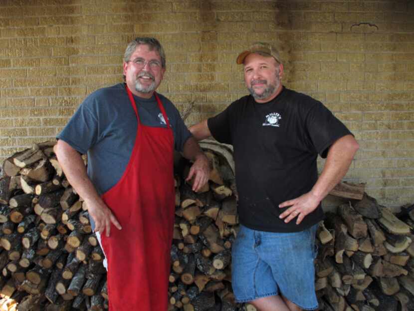 Owner Dirk Miller, left, and pitmaster Robert Reid pose by the woodpile at Miller's...
