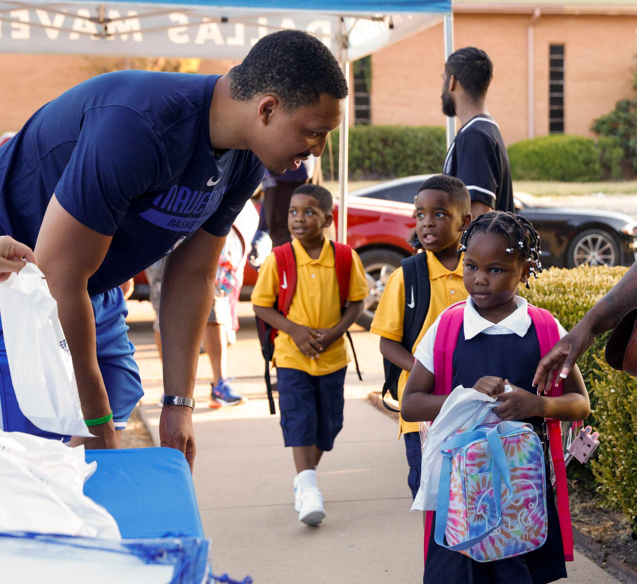 Dallas Mavericks forward Grant Williams (left) greets Amberly T., 6, as he hands out school...