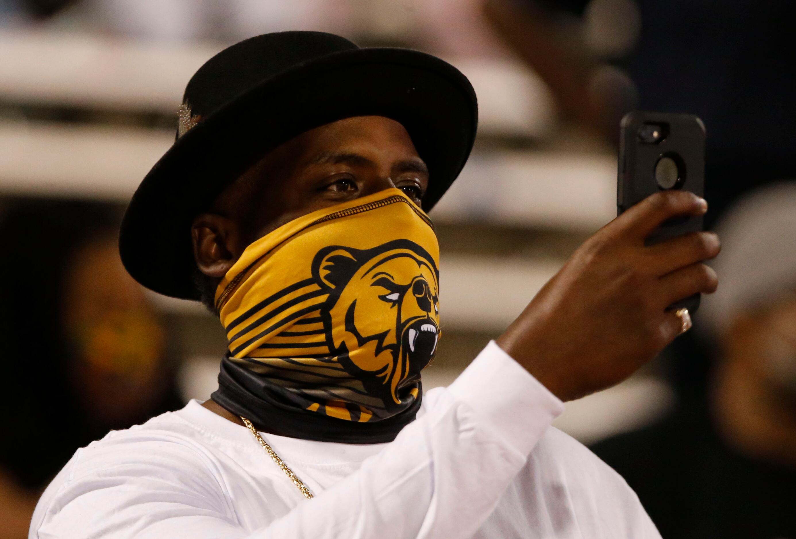 A South Oak Cliff fan clad in a Golden Bears facemask takes a mobile phone photograph before...
