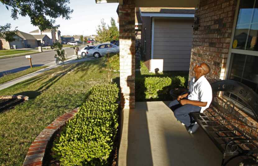 John Thomas Jr., 12, sits on the front porch of his house in one of the neighborhoods...