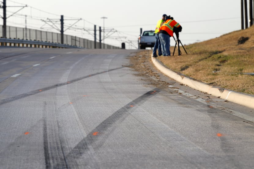 Tire skid marks are seen leaving the road as news cameraman film the area where a single...