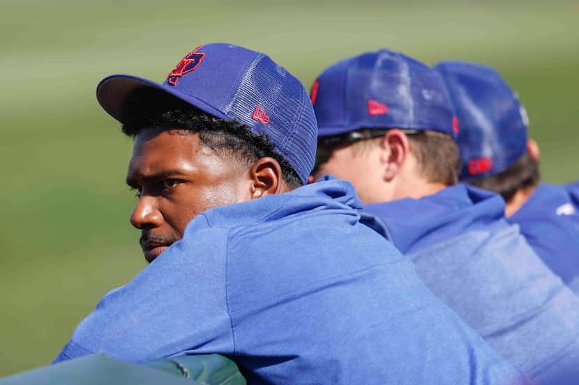 Texas Rangers pitcher Kumar Rocker sits in the dugout during spring training game against...