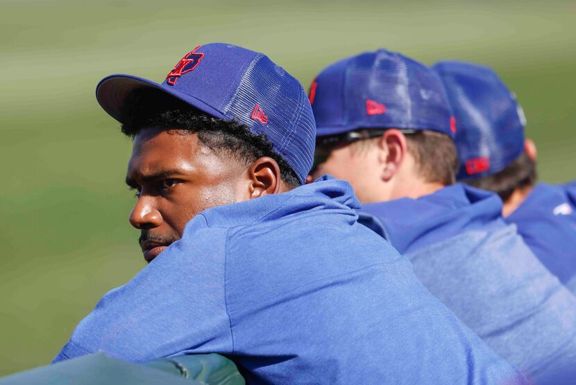Texas Rangers pitcher Kumar Rocker sits in the dugout during spring training game against...