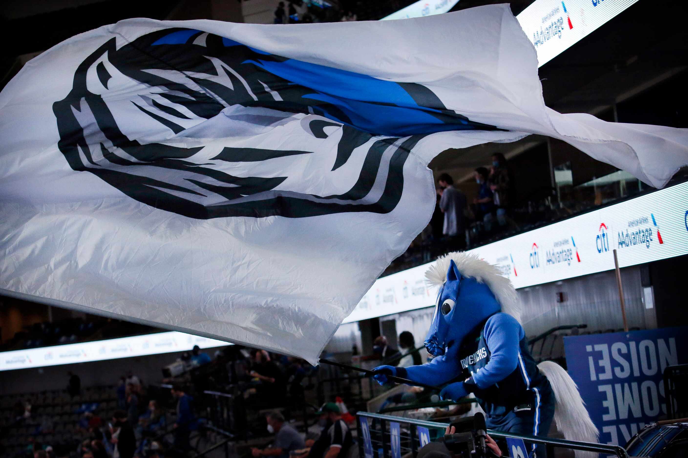 Dallas Mavericks mascot Champ waves the team flag from the main concourse as the players are...