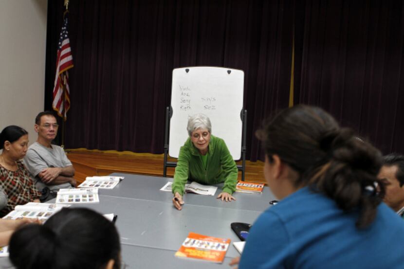 Pat French (center) passes out materials while teaching English to immigrants at Manske...