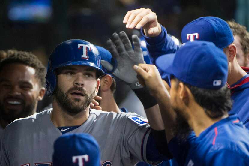 Texas Rangers' Mitch Moreland is greeted in the dugout, after hitting a solo home run off...