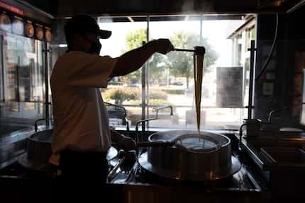 Aki Matsuo, director of culinary for Marugame, removes freshly boiled noodle dough as he...