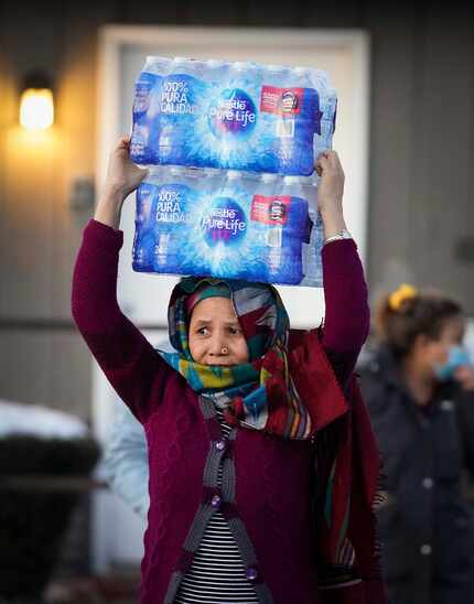 Una mujer carga un paquete con botellas de aguas en un centro de distribución en Literacy...