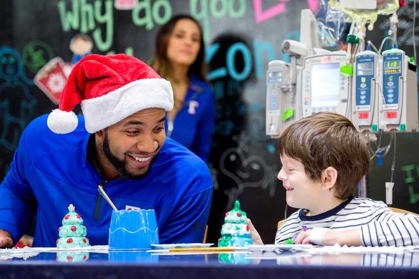 Texas Rangers shortstop Elvis Andrus laughs with Sebastian Gardner, 5, while they paint...