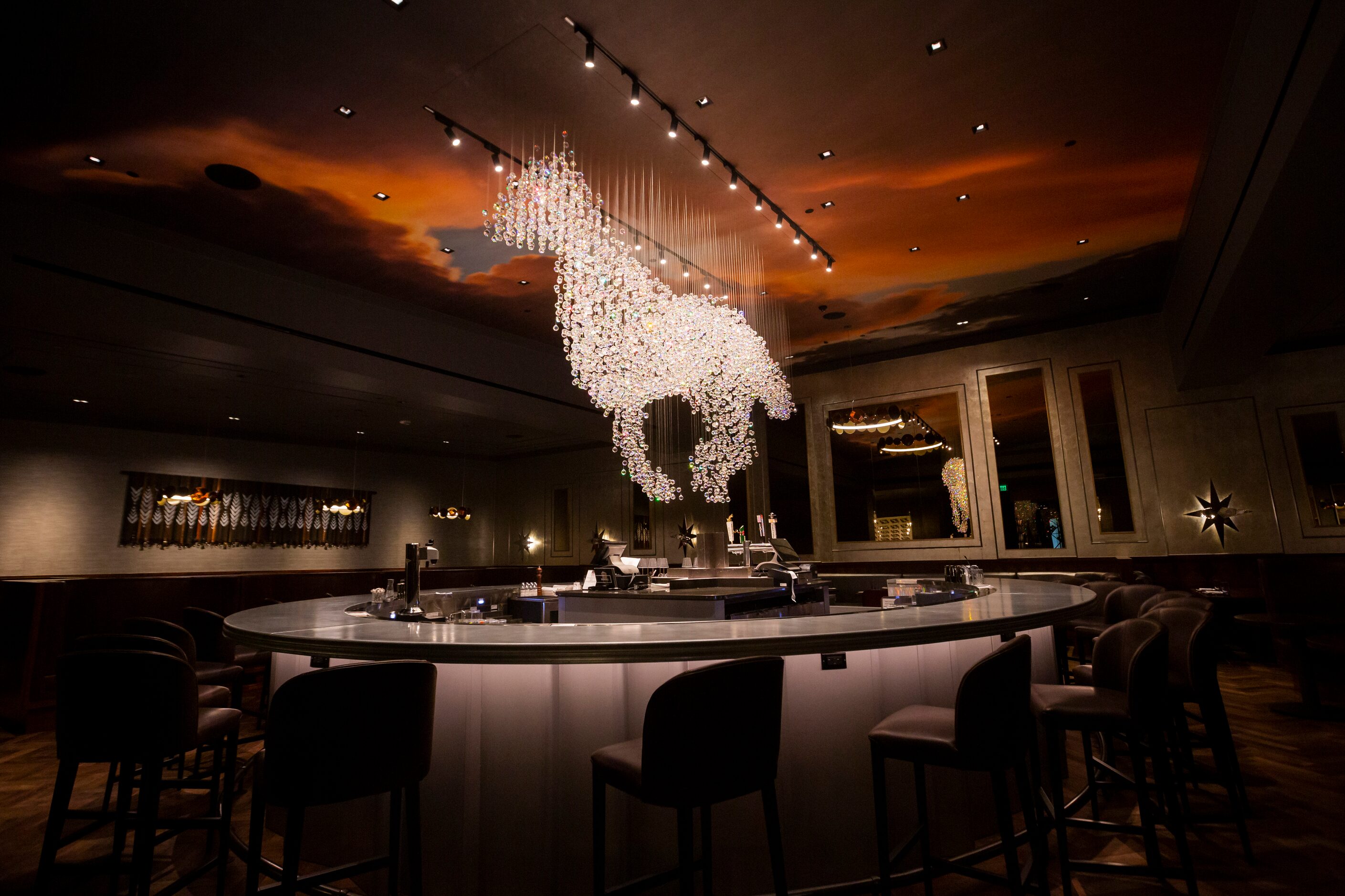 A hand-cut crystal horse chandelier hangs over the horseshoe-shaped bar at the Trick Rider...