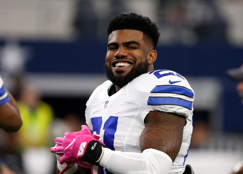 Dallas Cowboys' Ezekiel Elliott smiles as he talks with teammates during warm ups before an...