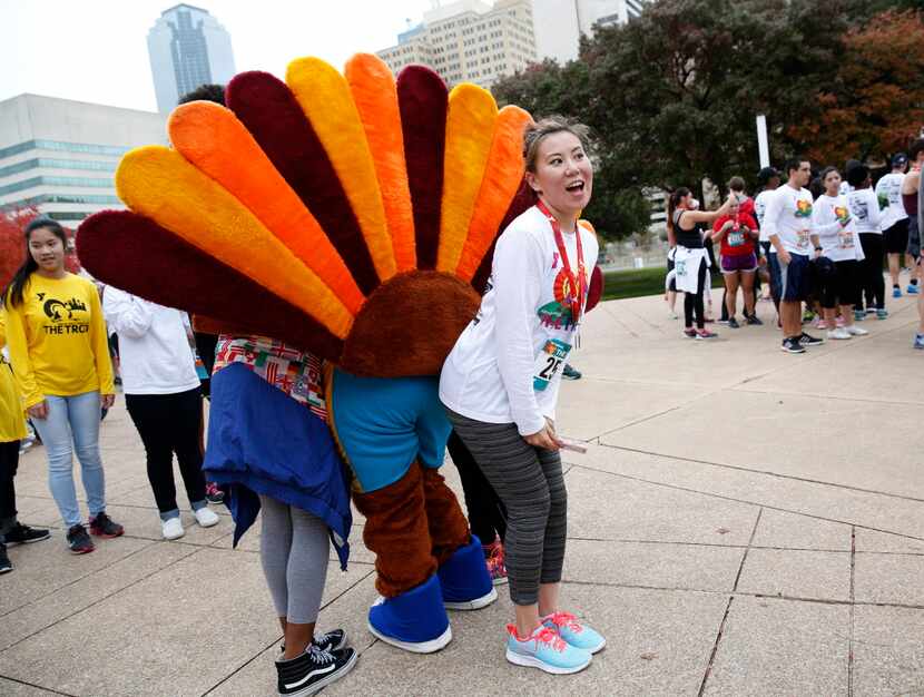 Violet Ye poses for a photo with the turkey mascot at the Dallas YMCA Turkey Trot in...