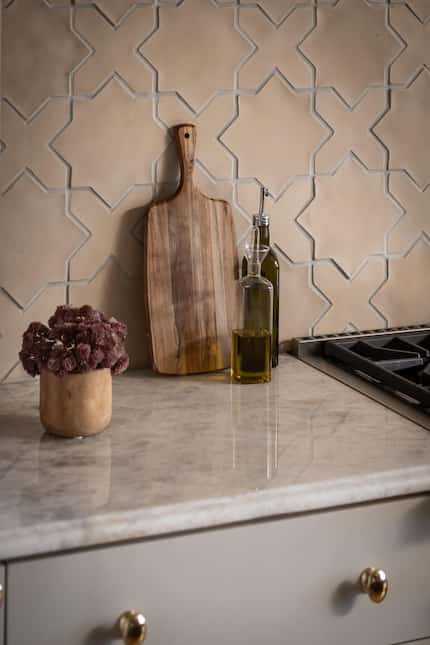 A terracotta star-and-cross pattern backsplash make for a textural focal point in this...