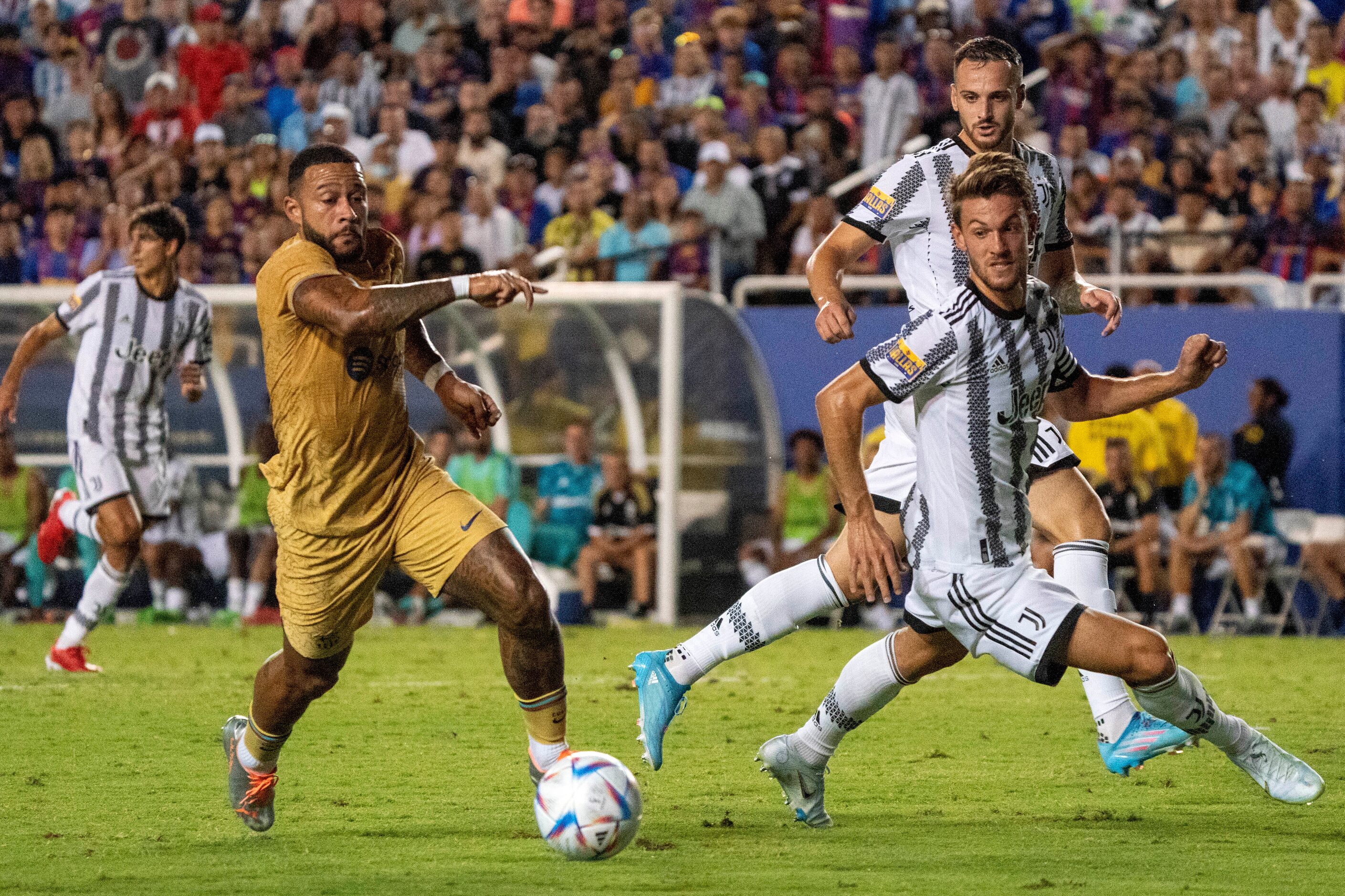 Barcelona forward Memphis Depay dribbles past Juventus defenders Daniele Rugani, foreground,...