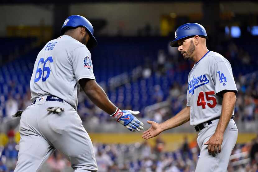 MIAMI, FL - MAY 15: Yasiel Puig #66 of the Los Angeles Dodgers slaps hands with third base...