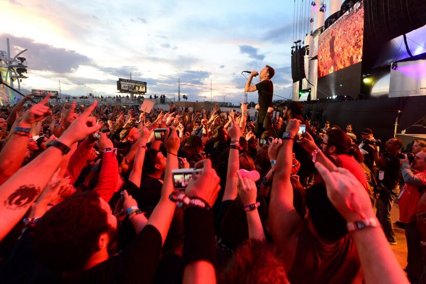 Fans gesture as they watch Rise Against, fronted by lead singer Tim Mcllrath (R), perform on...