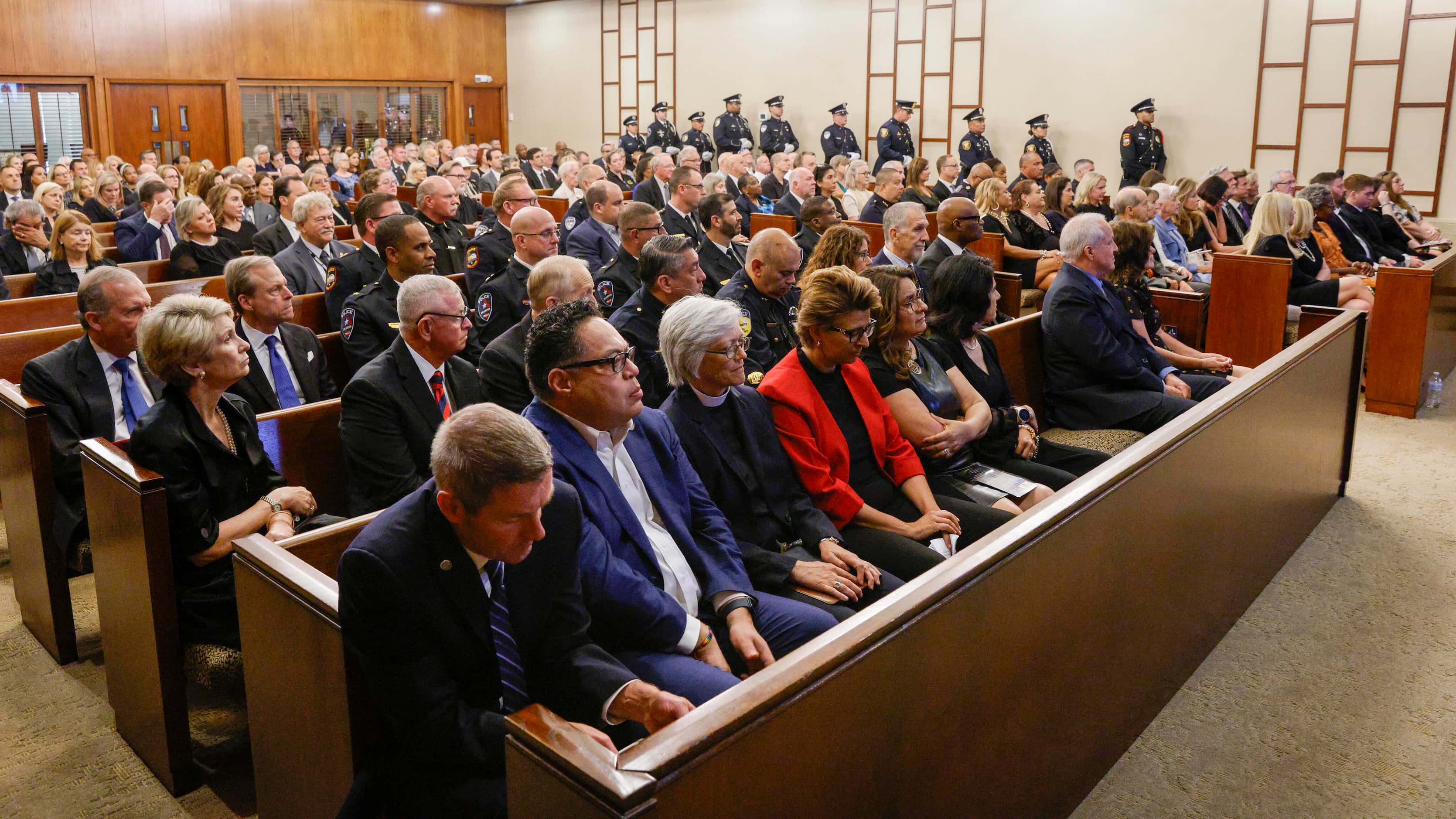 Members of law enforcement, family and friends listen to a eulogy during a funeral service...