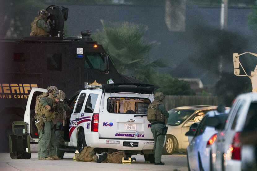 Law enforcement officers surround a shooting suspect in his car Wednesday, July 9, 2014, in...