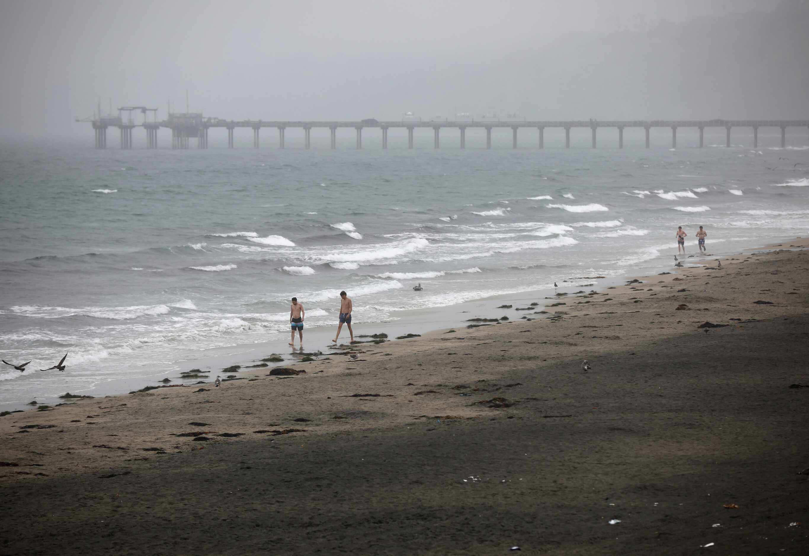 Varias personas caminan en la costa de La Jolla durante el paso de la tormenta tropical...