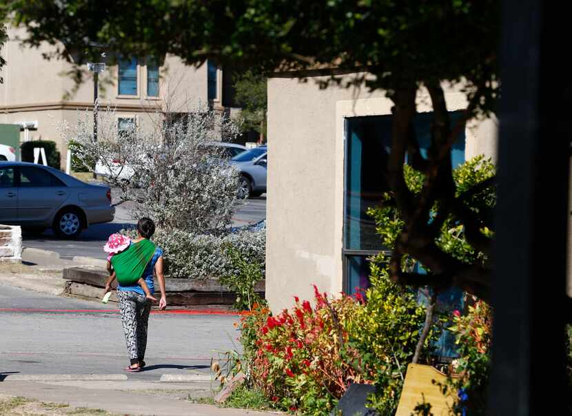 A woman walks with her baby in The Ivy Apartments in the Vickery Meadow neighborhood.