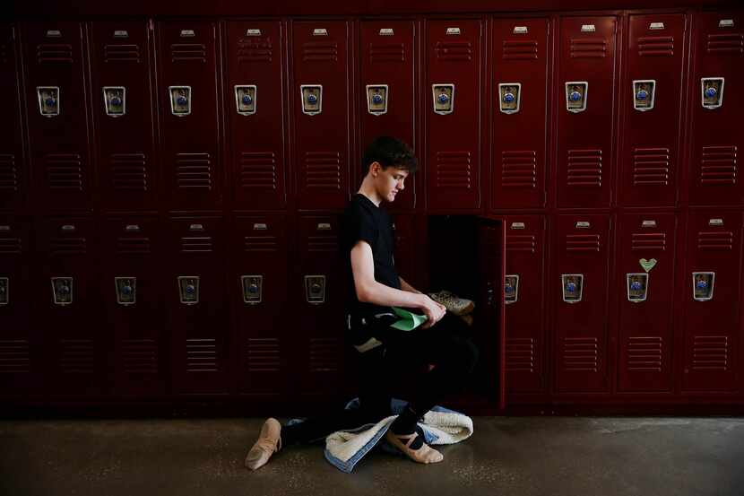 Dancer Lucas Dyson, a junior, kneels by his locker in-between classes.  