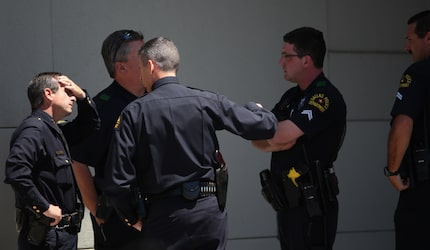 Interim Dallas Police Chief David Pughes, with his hand on his forehead, gathered with...