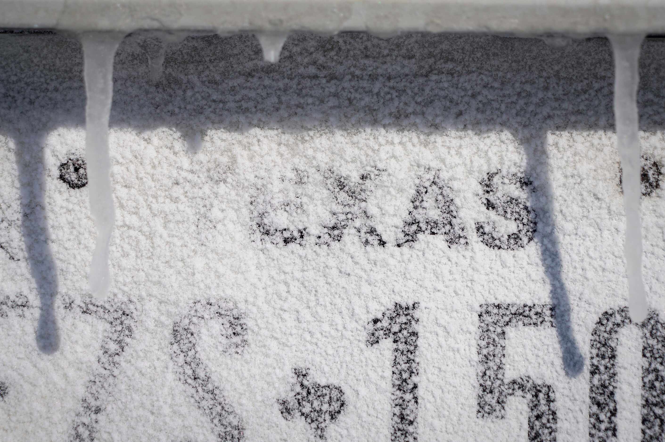 Icicles hang over a Texas license plate on a car after winter storm brought snow and...