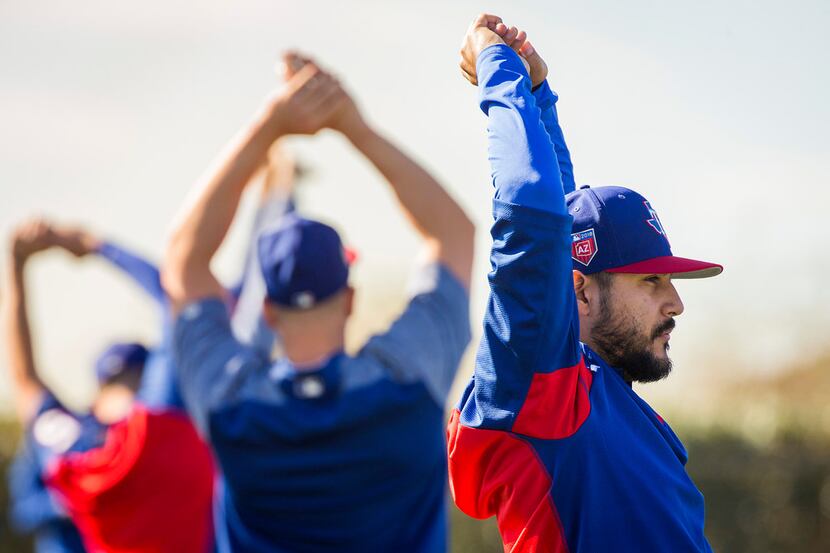 Texas Rangers pitcher Martin Perez stretches with teammates during a spring training workout...