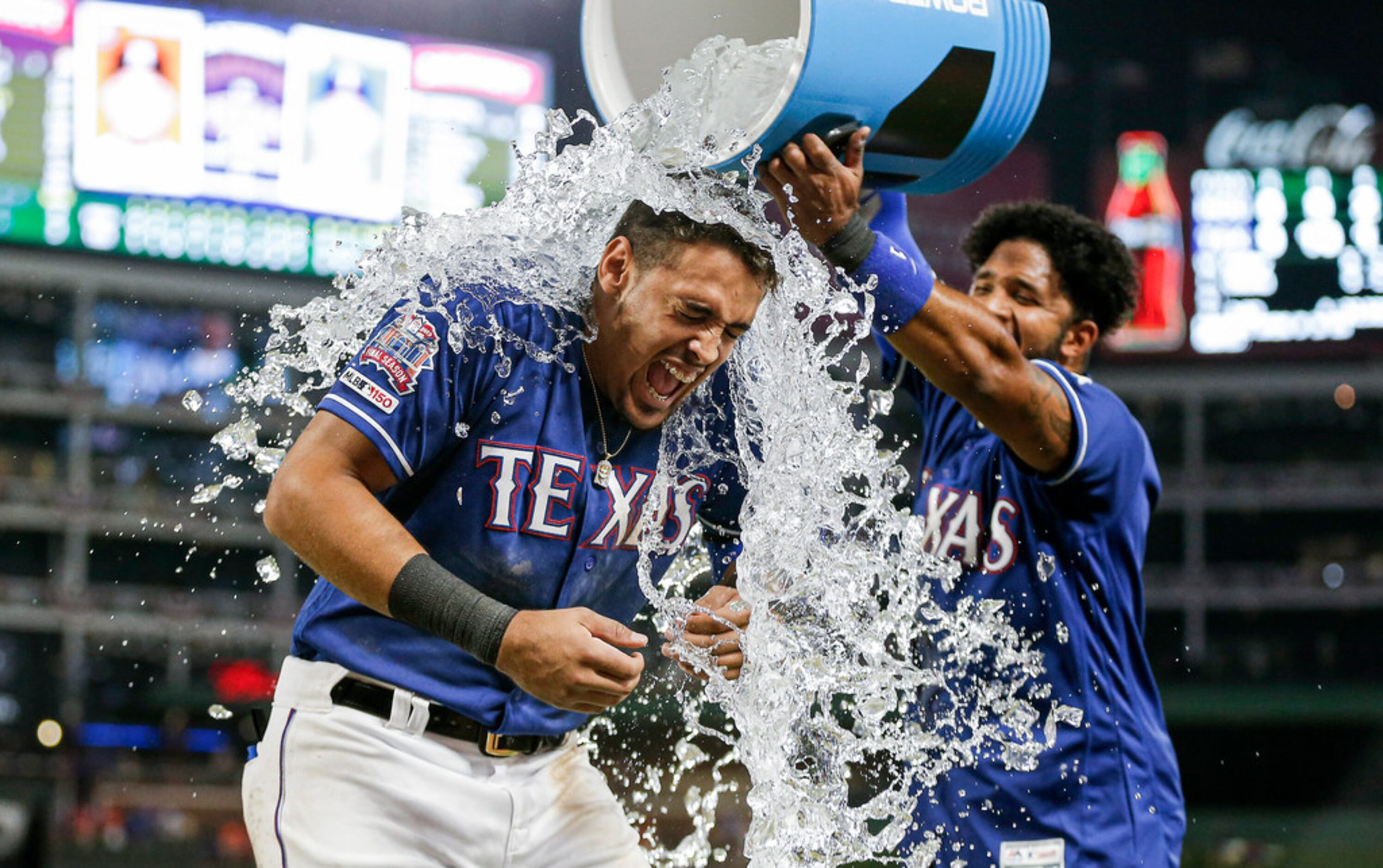 Texas Rangers' Ronald Guzman, left, is doused by teammate Elvis Andrus, right, after a...