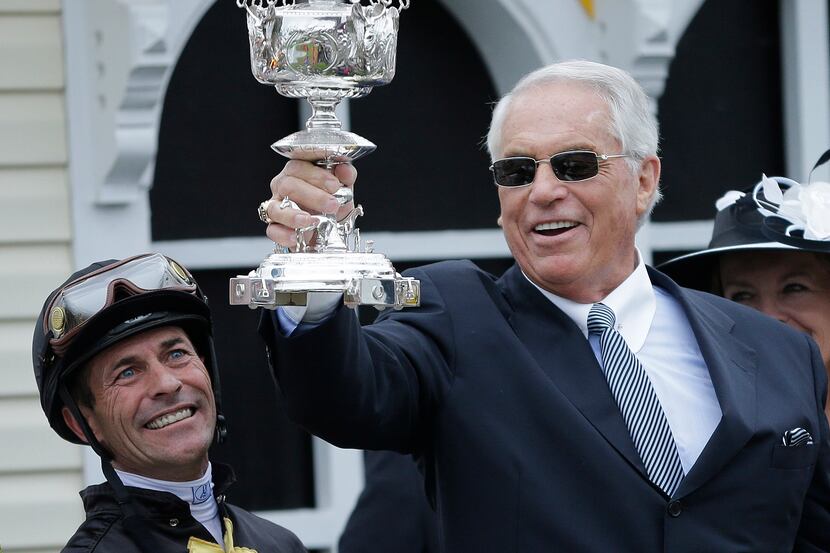 Jockey Gary Stevens, left, looks on as and trainer D. Wayne Lukas holds up a trophy in the...