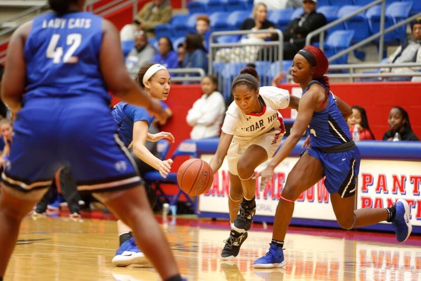 Cedar Hill point guard Dajinae McCarty (1) dribbles between the defense of a couple of Lady...