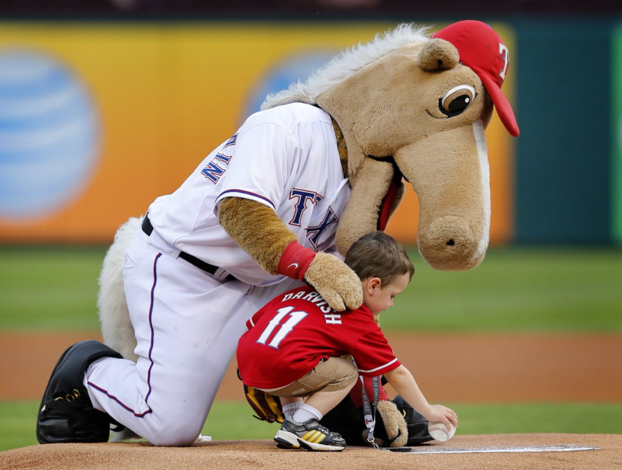 Texas Rangers mascot Captain helps 3 yr-old Keaton lloyd of McKinney deliver the game ball...