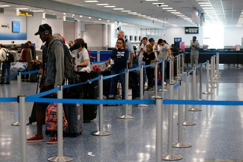 Travelers lined up Friday at the American Airlines counter at Miami International Airport....