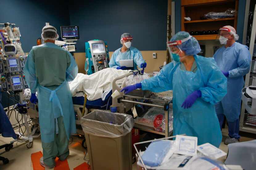 Led by Dr. Matt Leveno, left, a team of healthcare workers assesses an intubated patient in...