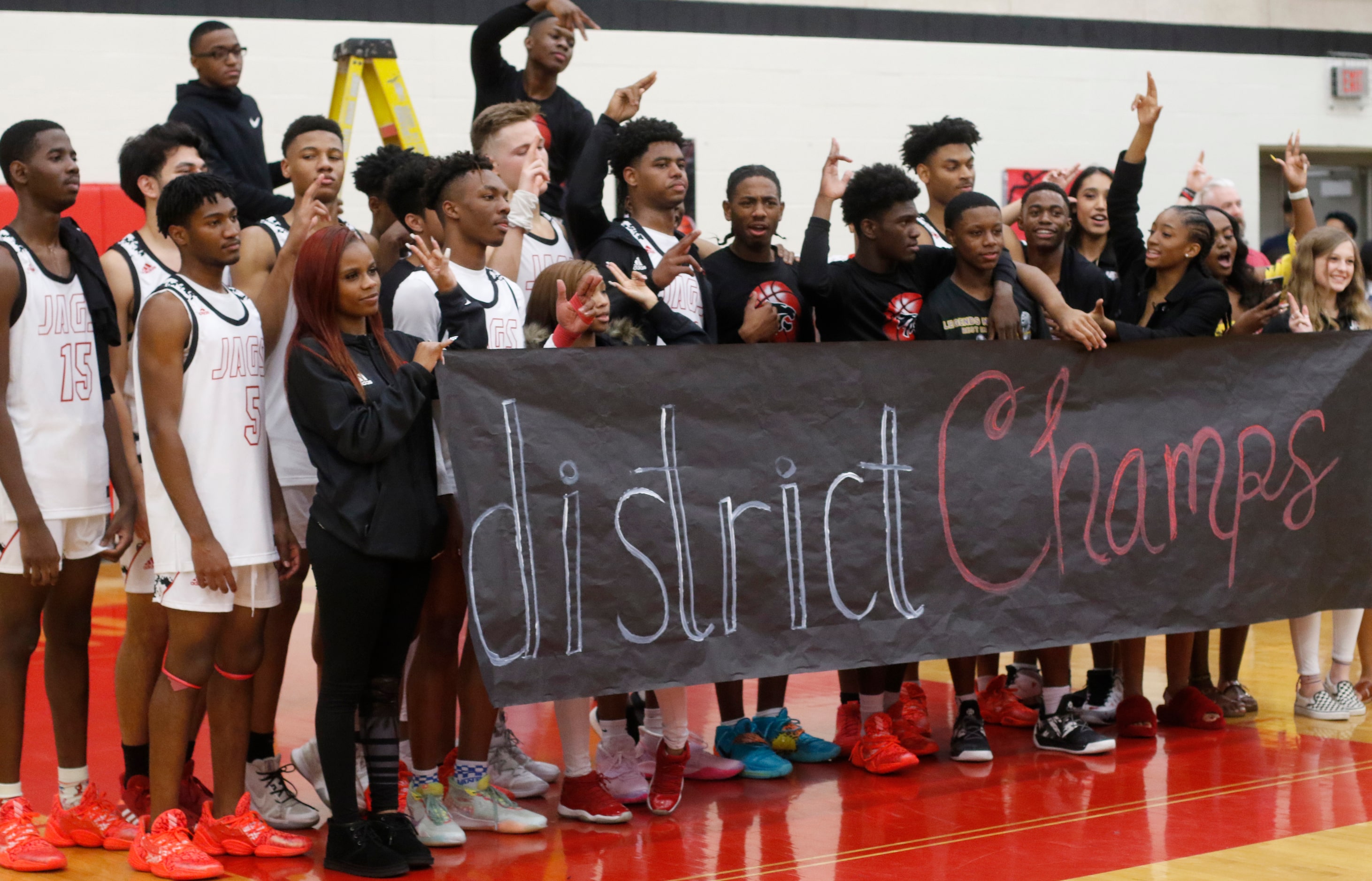 Members of the Mesquite Horn varsity basketball ream pose with fans and supporters behind a...