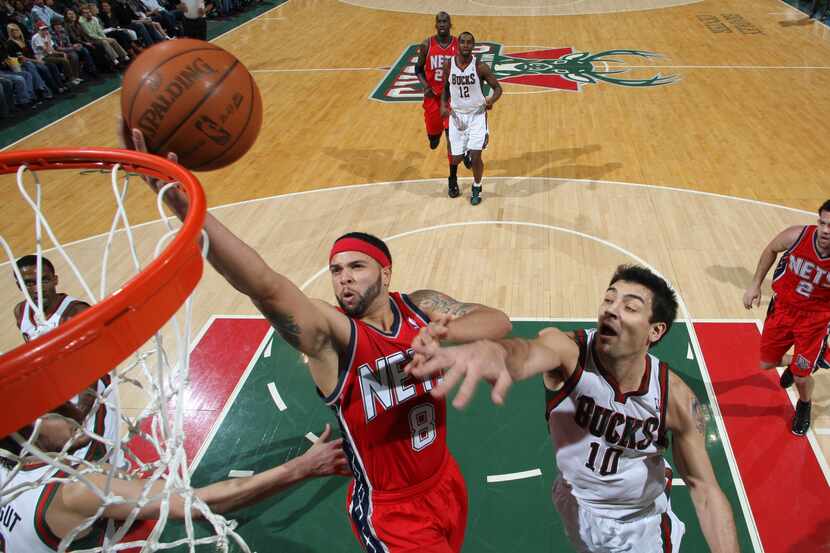 Nets point guard Deron Williams drives to the basket against Bucks guard Carlos Delfino on...