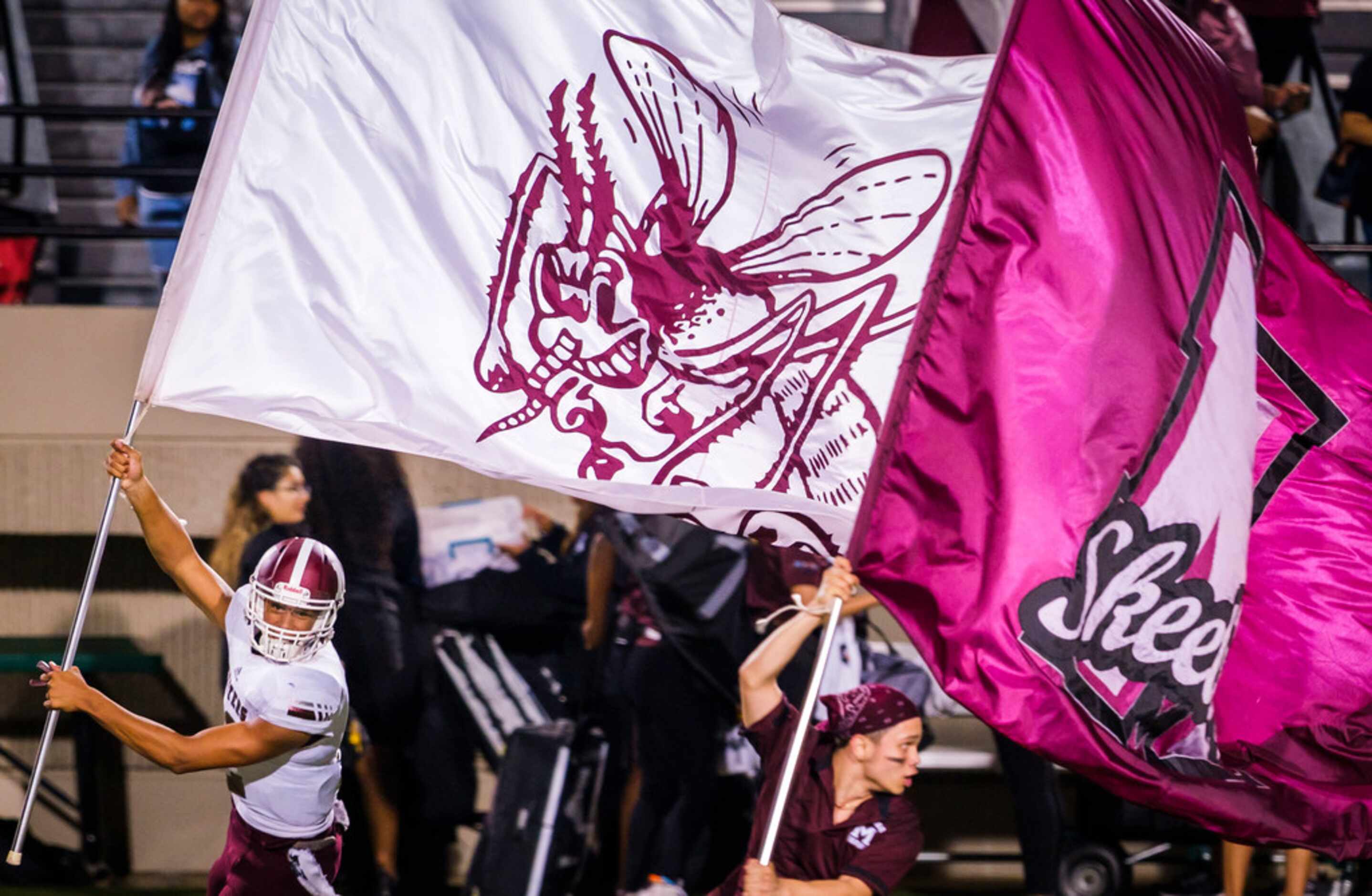 Mesquite quarterback Dylan Hillard-McGill (12) funs on the field with the team flag after a...