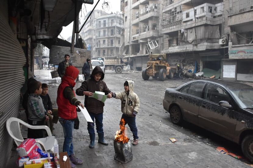 Syrian children gather around a fire as the Syrian government starts to clean up areas...