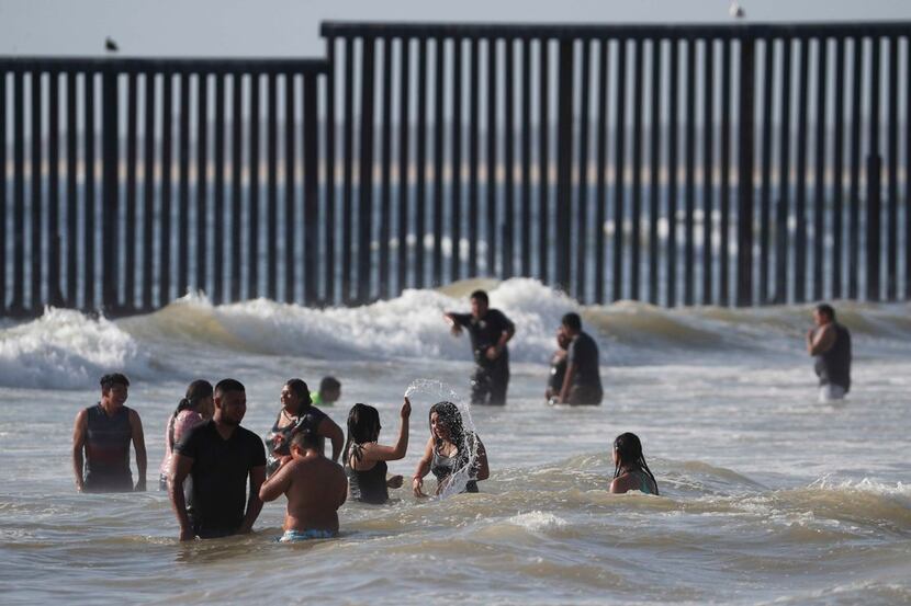 People enjoy the beach near the U.S. border wall in Tijuana, Mexico, Sunday, June 9, 2019. 