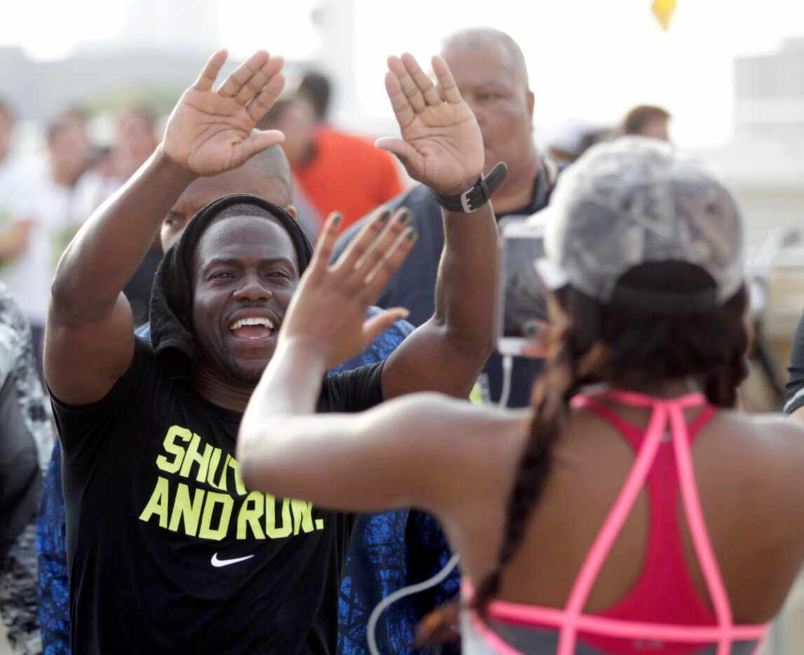 Kevin Hart high fives runners as they make their way in the Local Run With Hart running...