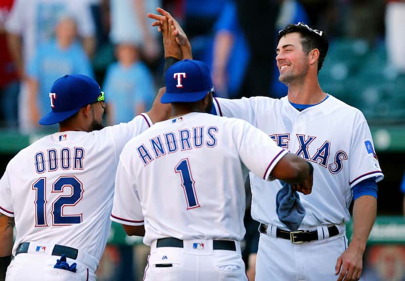 Texas Rangers starting pitcher Cole Hamels (right) gives second baseman Rougned Odor (12) a...
