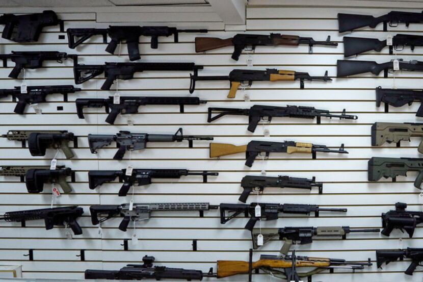 Dozens of semi-automatic rifles line a wall in a gun shop Tuesday, Nov. 7, 2017, in...