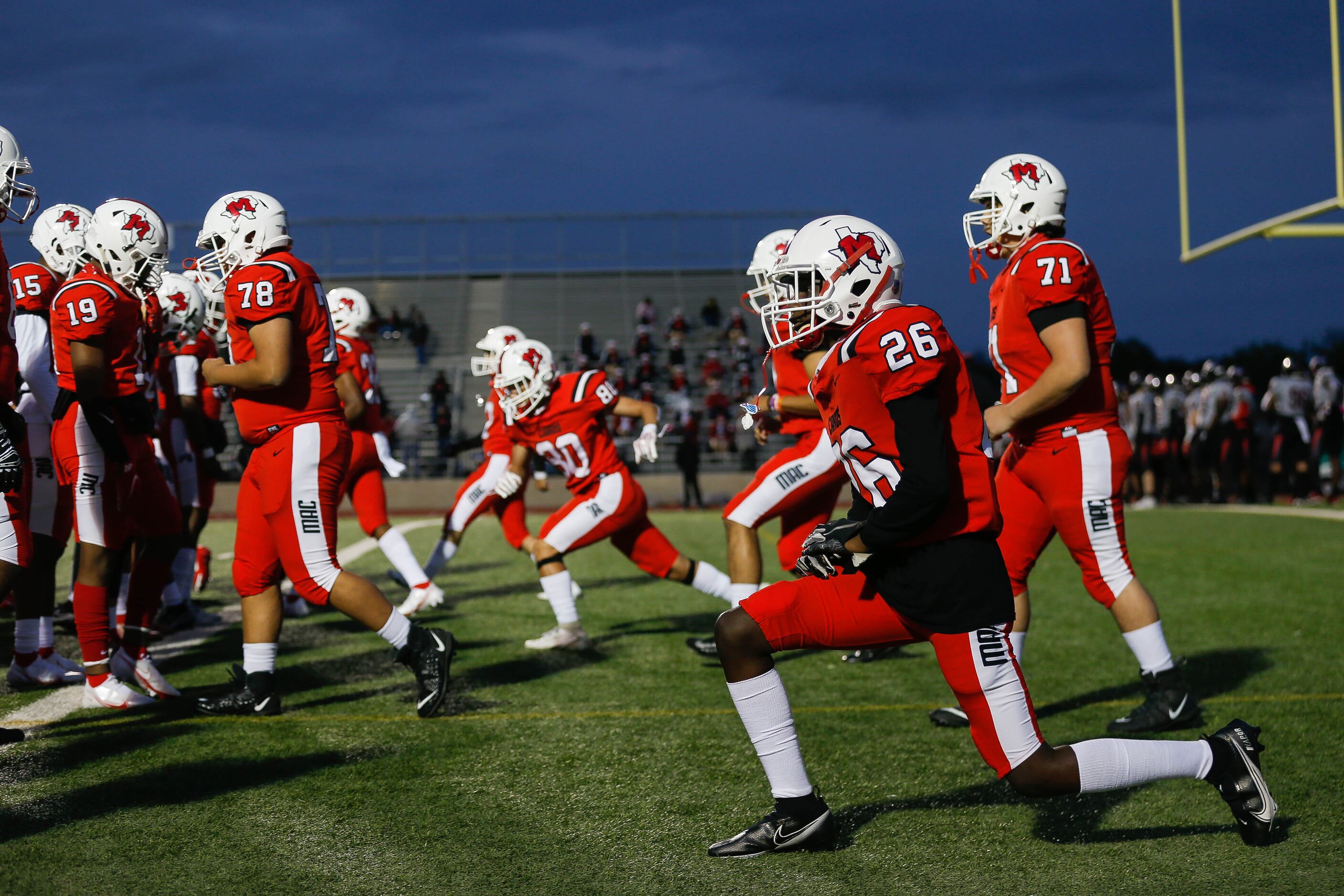 Irving MacArthur High School players stretch before a football game against Lake Highlands...