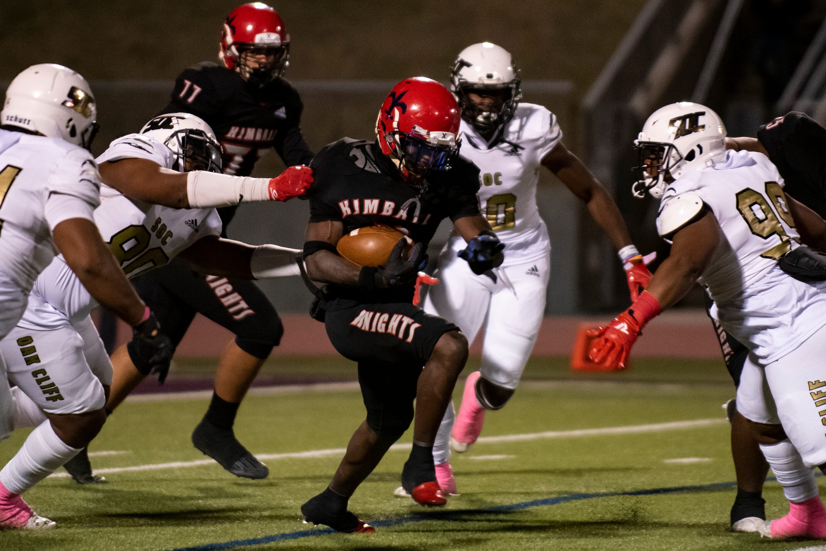 Kimball senior Niteroi Davis (4) is dragged down by South Oak Cliff junior Keith Smith (80)...